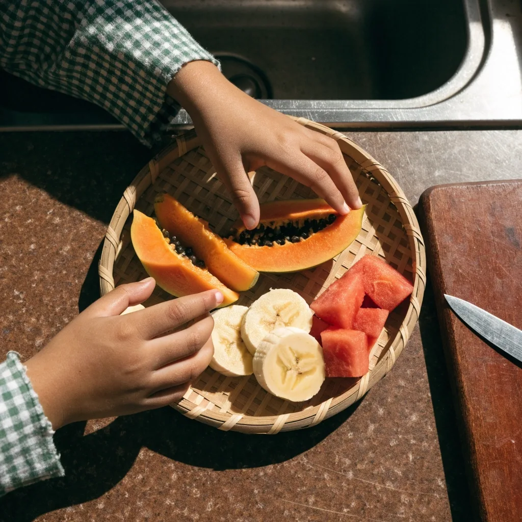 Piring buah potong dengan pepaya, pisang, dan semangka di atas meja kayu